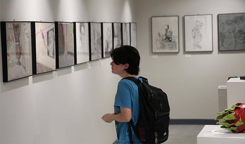 Student admiring the art frames hanging on the wall.