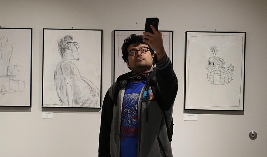 Student taking a selfie with the black and white art drawings.