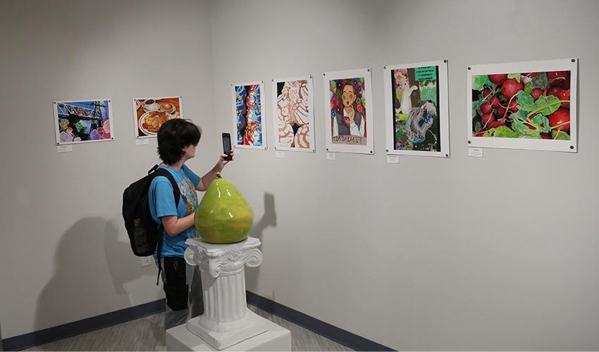 Student taking a picture of the colorful art paintings.